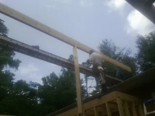 Carpenter setting a ridge beam over a new addition frame — Ice Dam Removal by Roofing Brothers in Claremont