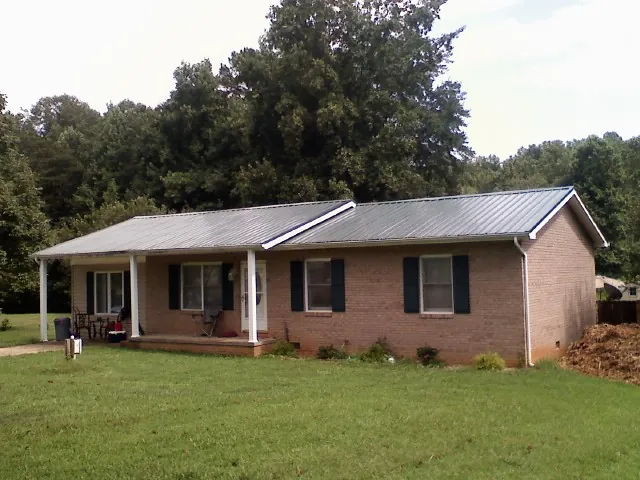 Gray metal roof on a brick ranch house with a side carport in Claremont