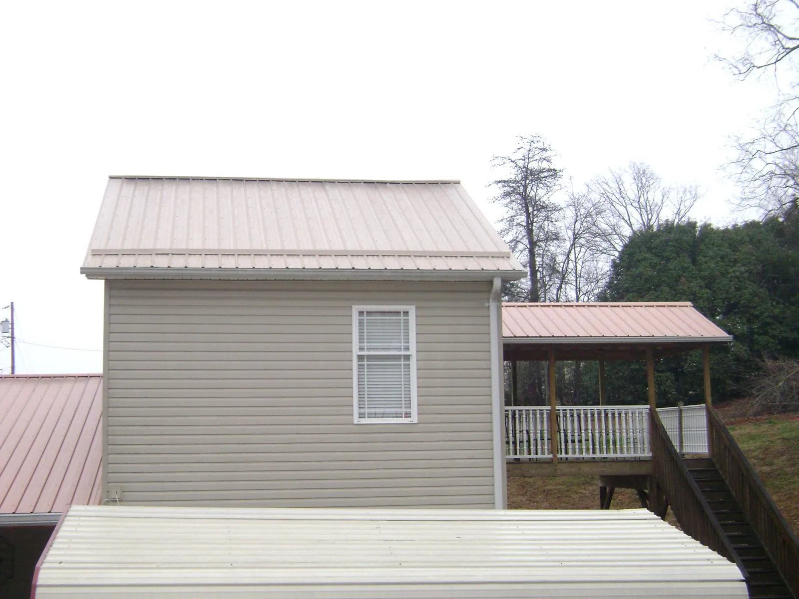 Tan metal roofs on a two story addition and attached porch, from a Roof Replacement job in Claremont